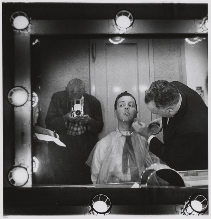[Weegee photographing Art Ford in a mirror, having makeup applied]