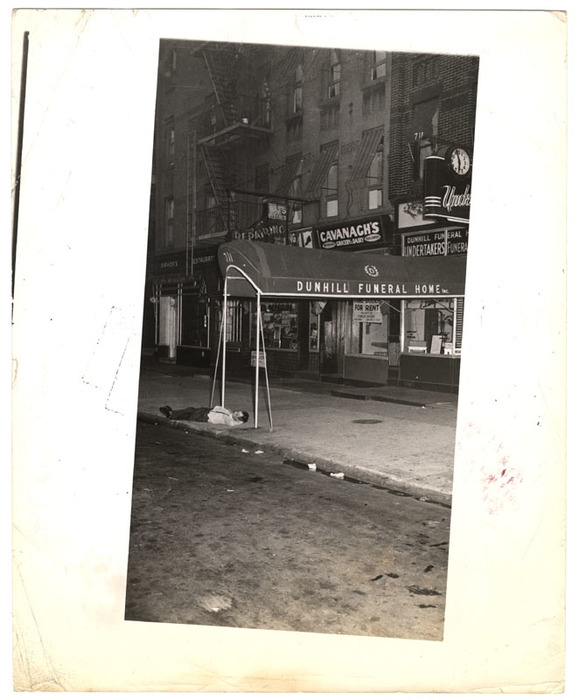 [Man sleeping on pavement in front of Dunhill Funeral Home, New York]