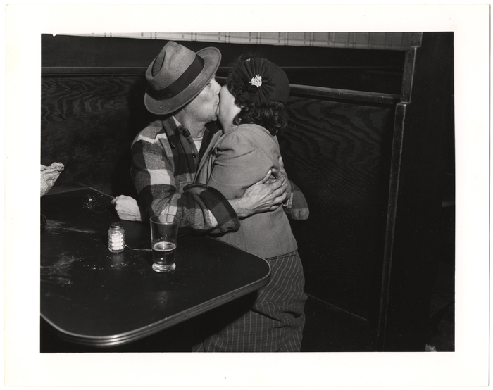 [Man and woman kissing in booth]