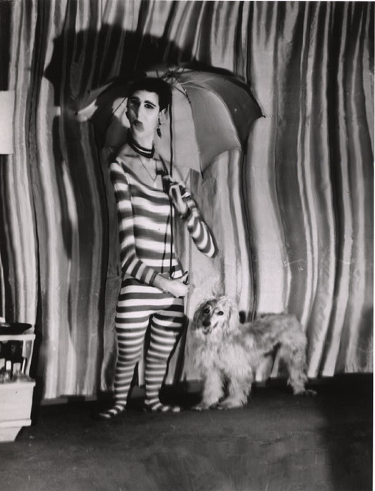 (Model wearing striped jumpsuit, with dog and umbrella)