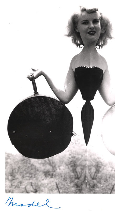 Blonde model on top of a rocky hill with round bag