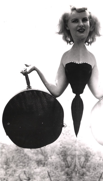 Blonde model on top of a rocky hill with round bag