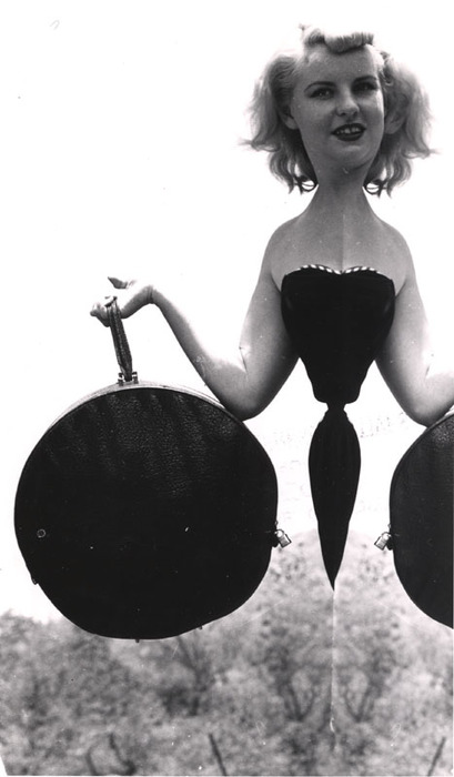 Blonde model on top of a rocky hill with round bag