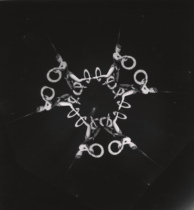 (Acrobat, hanging from her hair, with three hoops)