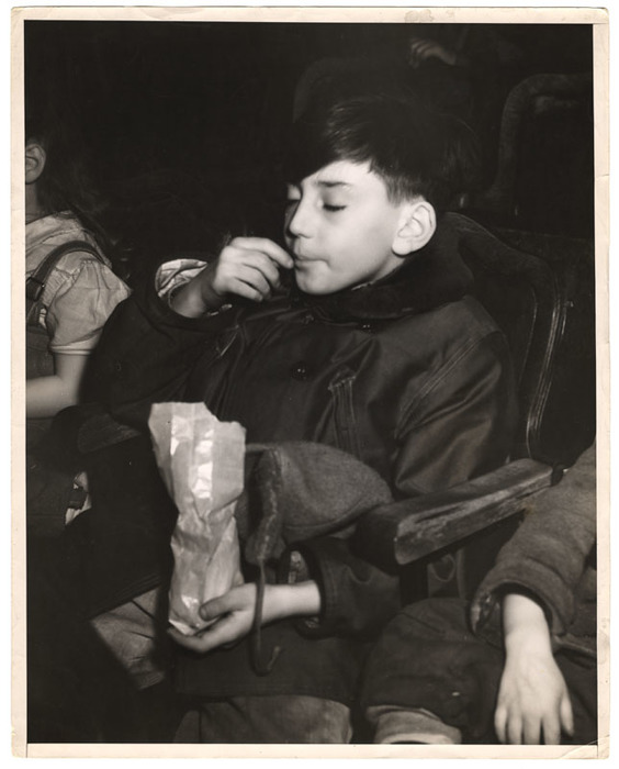 Boy with eyes closed eating in a movie theatre