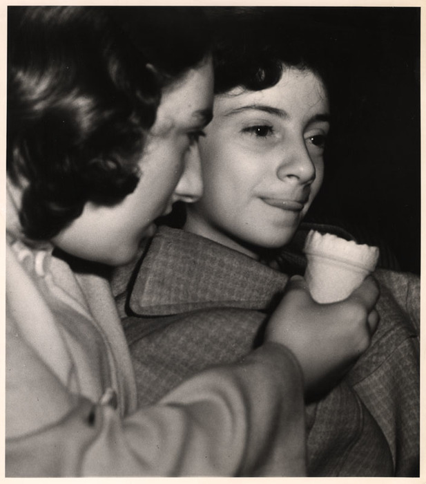 Two girls eating ice cream in a movie theatre