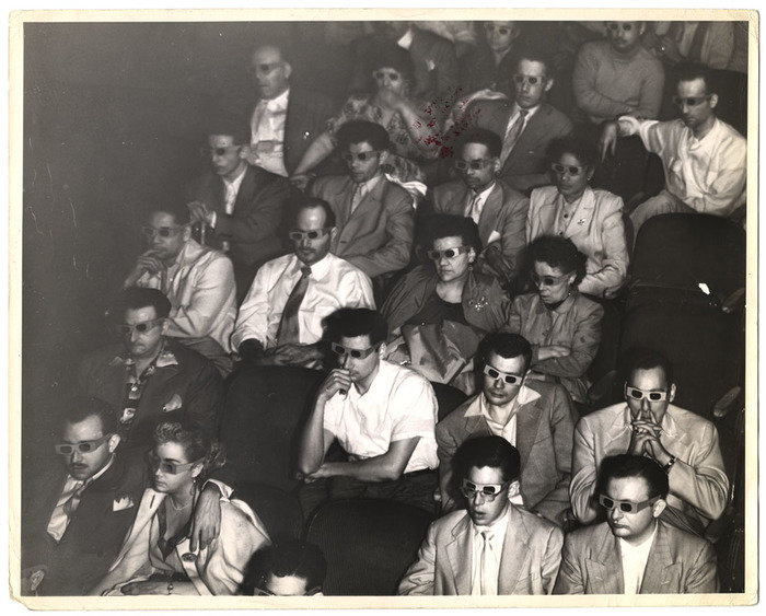 [Movie theater audience wearing 3-D glasses]