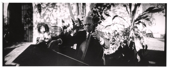 [Widescreen image of cellist performing outside in Louis de Rochemont's film "Windjammer"]