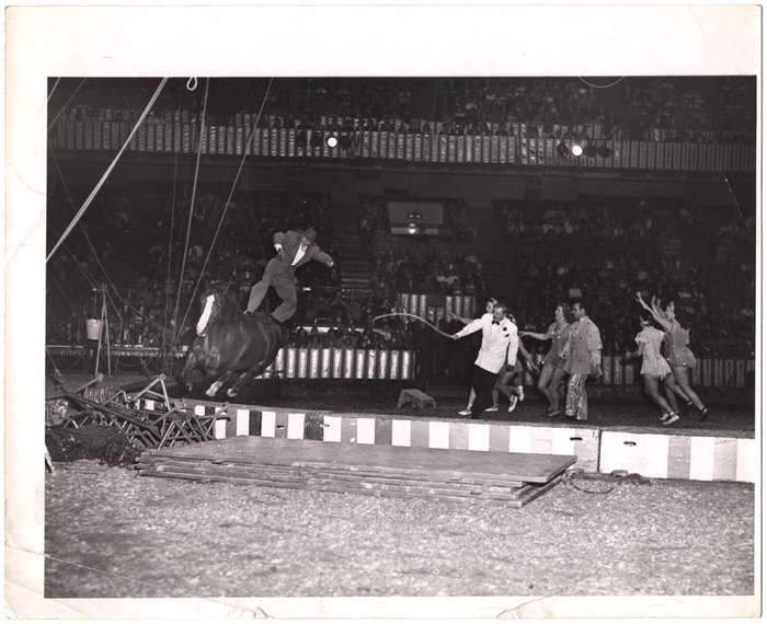 [Man on horse with performers in circus]