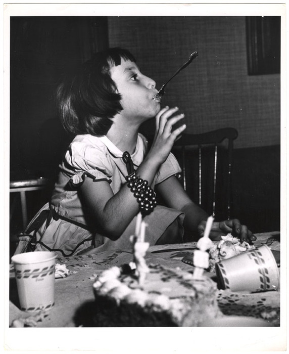 Girl with fork in her mouth at birthday party