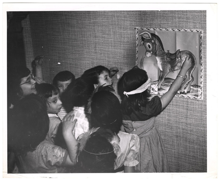 Children at a birthday party play pin-the-tale-on-the-donkey