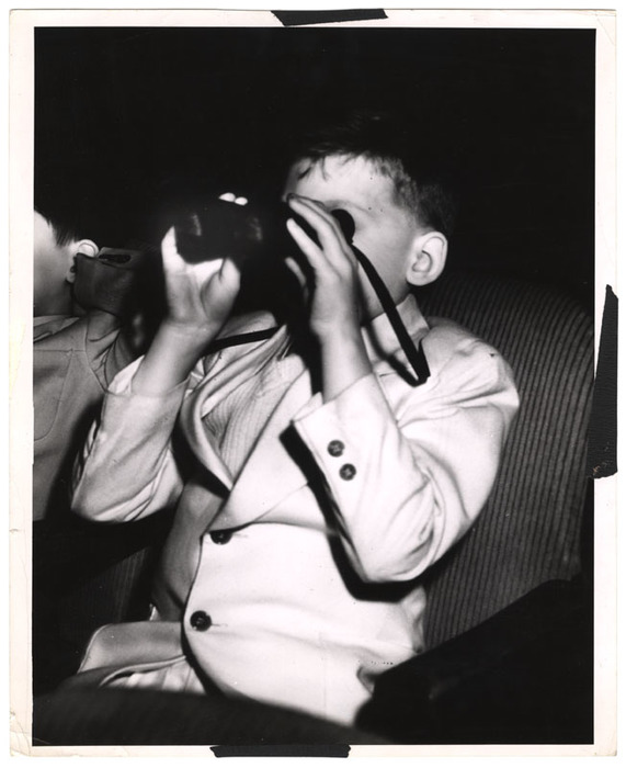 Boy looking through binoculars in a movie theatre