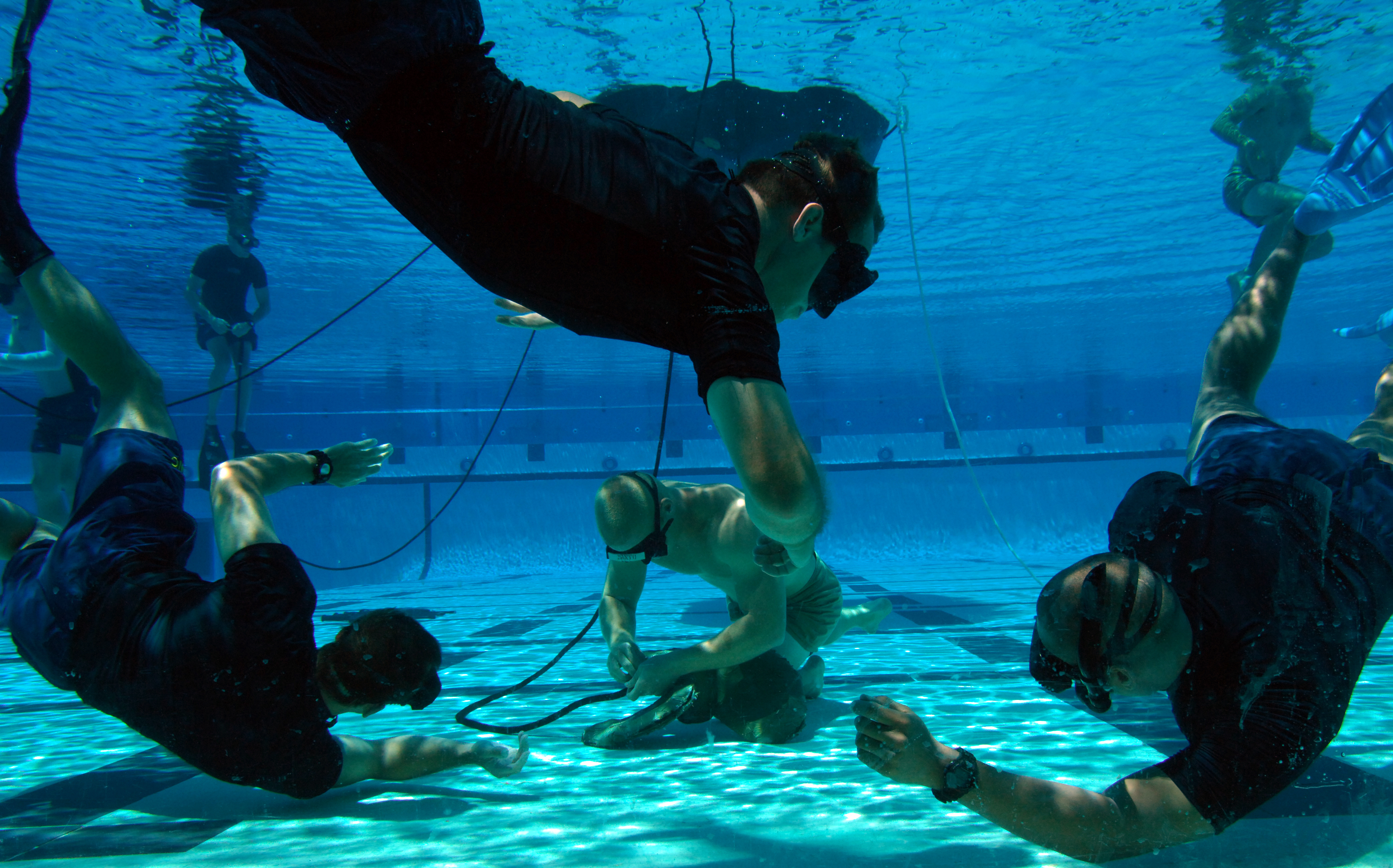 Instructors watch a Basic Crewman Training (BCT) student demonstrate knot-tying skills during water proficiency training at Naval Amphibious Base Coronado. BCT is the first phase of the Special Warfare Combatant-Craft Crewman (SWCC) training program. SWCCs operate and maintain the Navy's inventory of state-of-the-art, high-performance boats used to support SEALs in special operations missions worldwide. U.S. Navy photo by Mass Communication Specialist 2nd Class Christopher Menzie (Released)