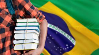menino segurando livros na frente de uma bandeira do brasil