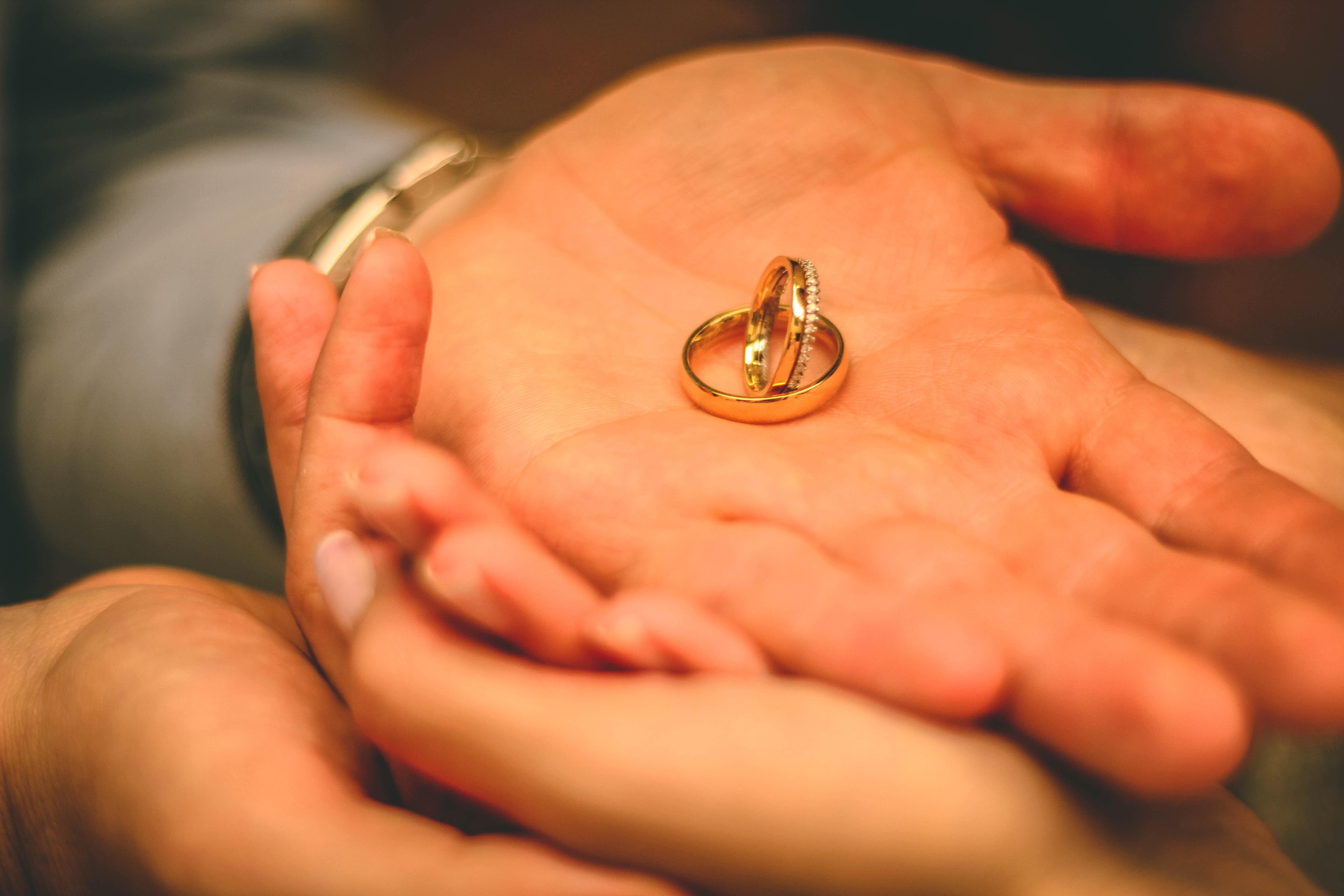 Two gold wedding bands nestled in the couple's hands