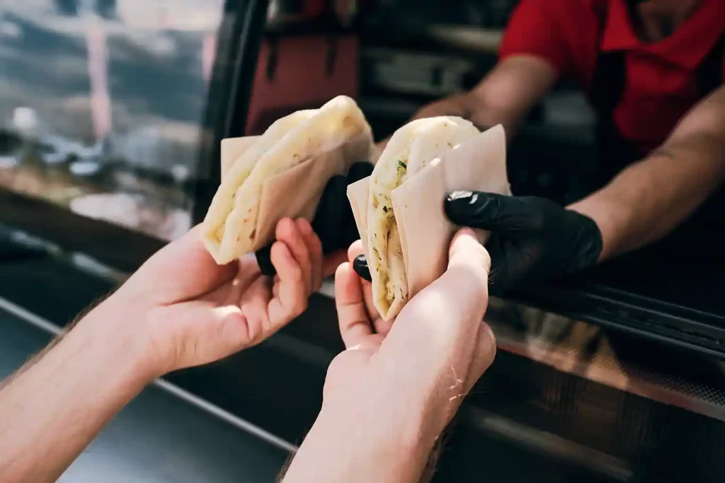 Tacos being handed to a customer.