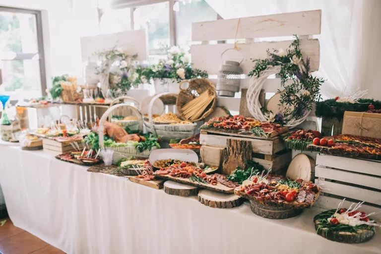 Catered table set up with plates of food and floral arrangements