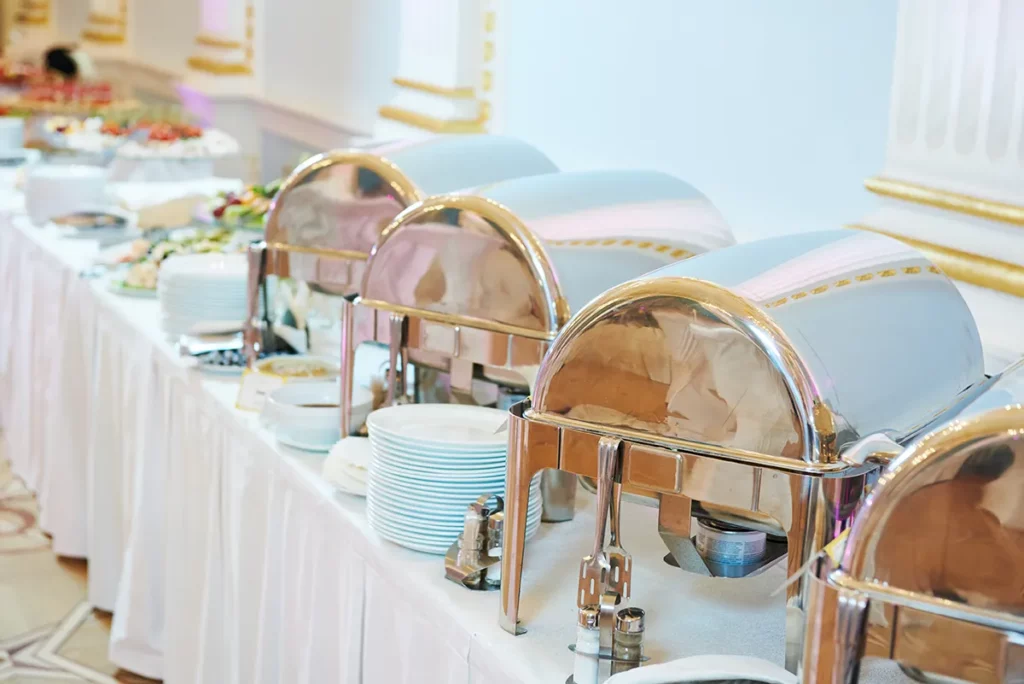 A shot of catering serving dishes on buffet tables covered in white tablecloths.