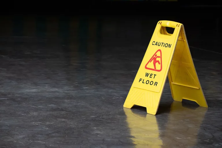 A wet floor sign placed on a gray concrete floor.