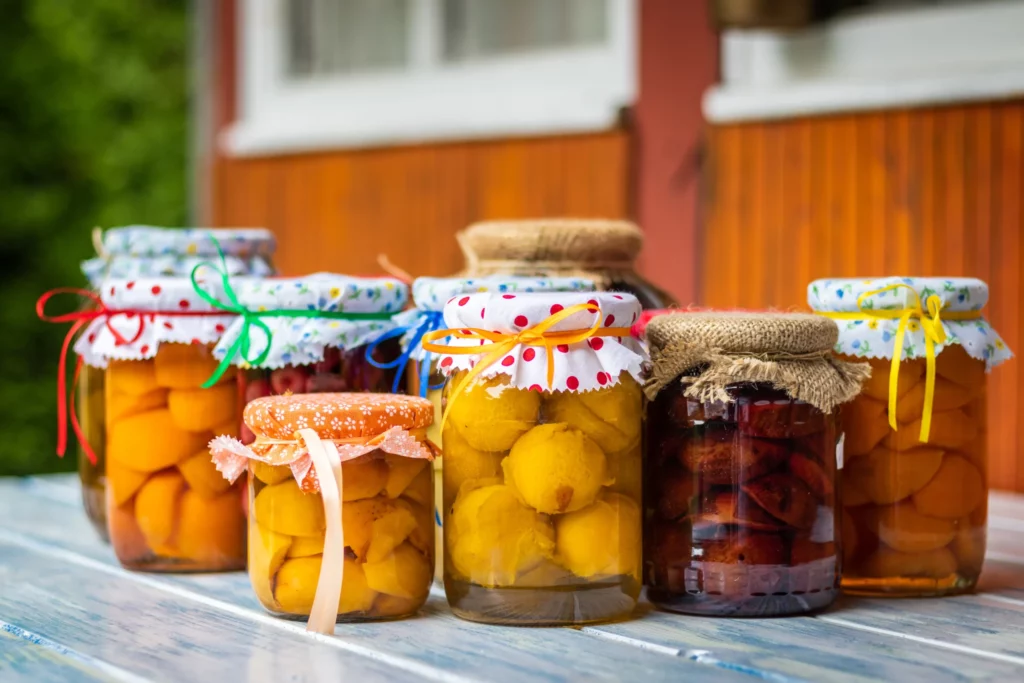 Jars of preserved fruit sitting on a blue wooden table outside.