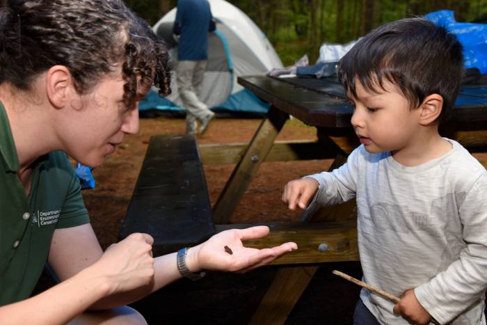 Camp Ambassador teaches a young child about local wildlife