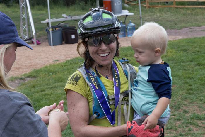 Chelsey Magness finished 3rd at the Telluride 100 MTB Race. She celebrates with son Max