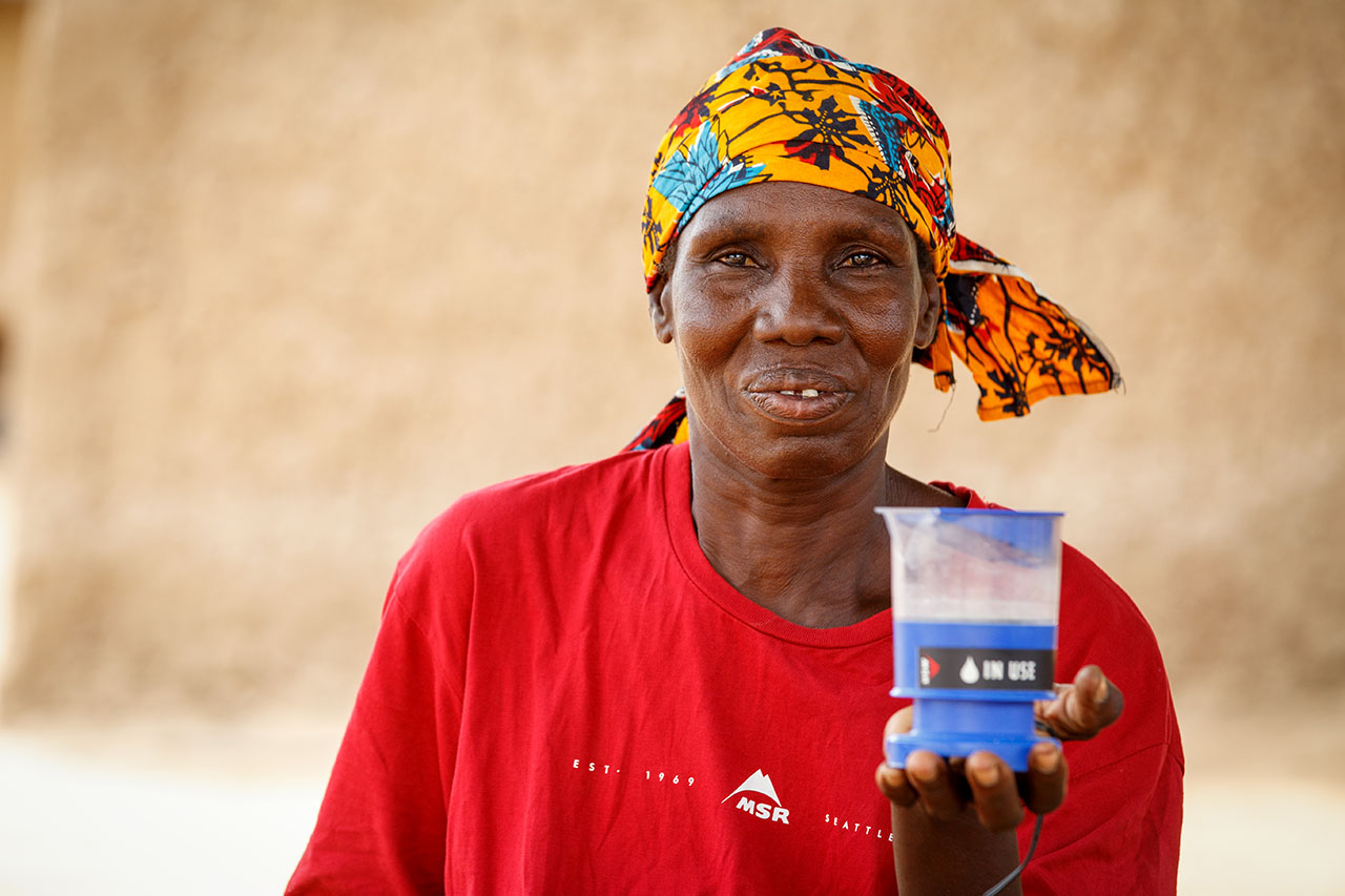 Sirakoro Chlorinator Hawa Traore, a volunteer, demonstrates how she uses the MSR SE 200 Community Chlorinator to make her village's water safer to cook with and drink.