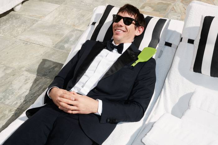 Alex Honnold lounging beach chair in a tux