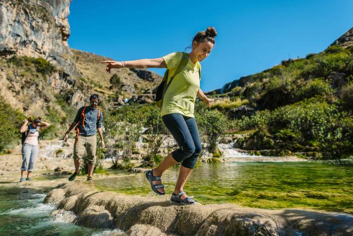 Person Hiking in Merrell Footwear Across a River