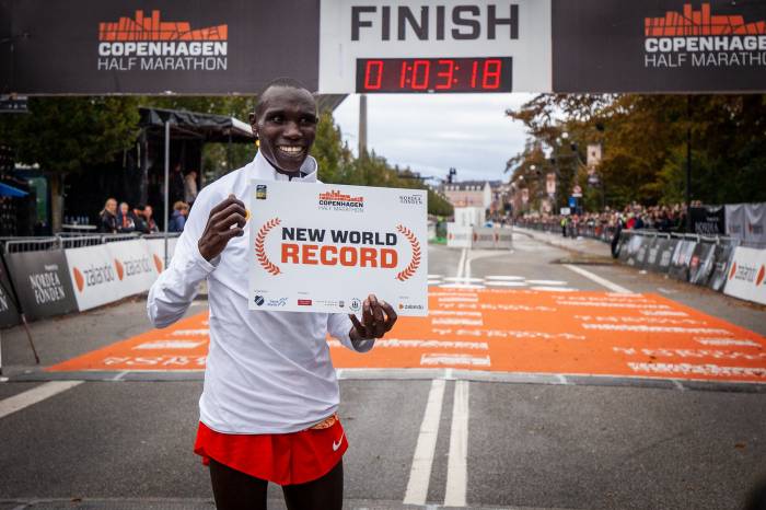 Geoffrey Kamworor holding world record sign at finish line