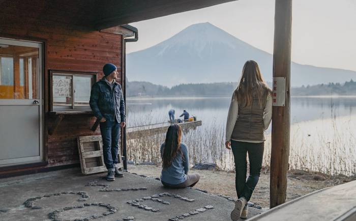 3 people on covered deck overlooking lake on cloudy day