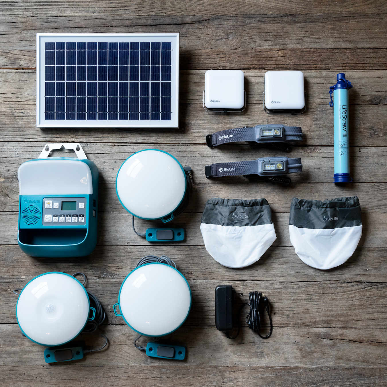 biolite prep kit with solar panel, life straw, headlamps, solar lights, and charger laid out on wood background