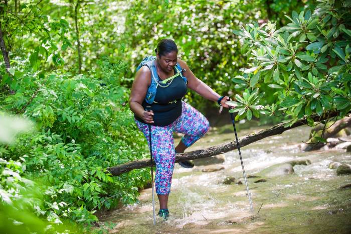 mirna valerio stepping over branch as she hikes through creek