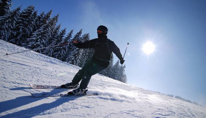 skier pointed downhill with bright sun in background