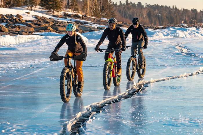 3 people riding 45NRTH fat bikes and winter gear across icy lake