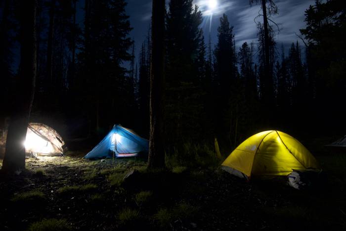 backcountry tents glowing at night under moon