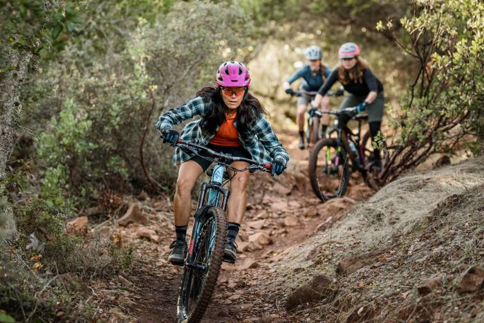 group of women mountain biking down trail in fall