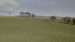 3 U.K. cyclists biking across field in Yorkshire