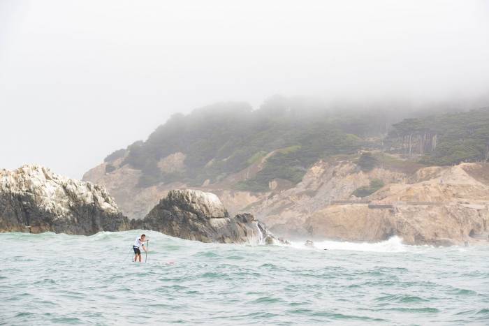 Woman paddling through waves in Heavy Water SUP Competition