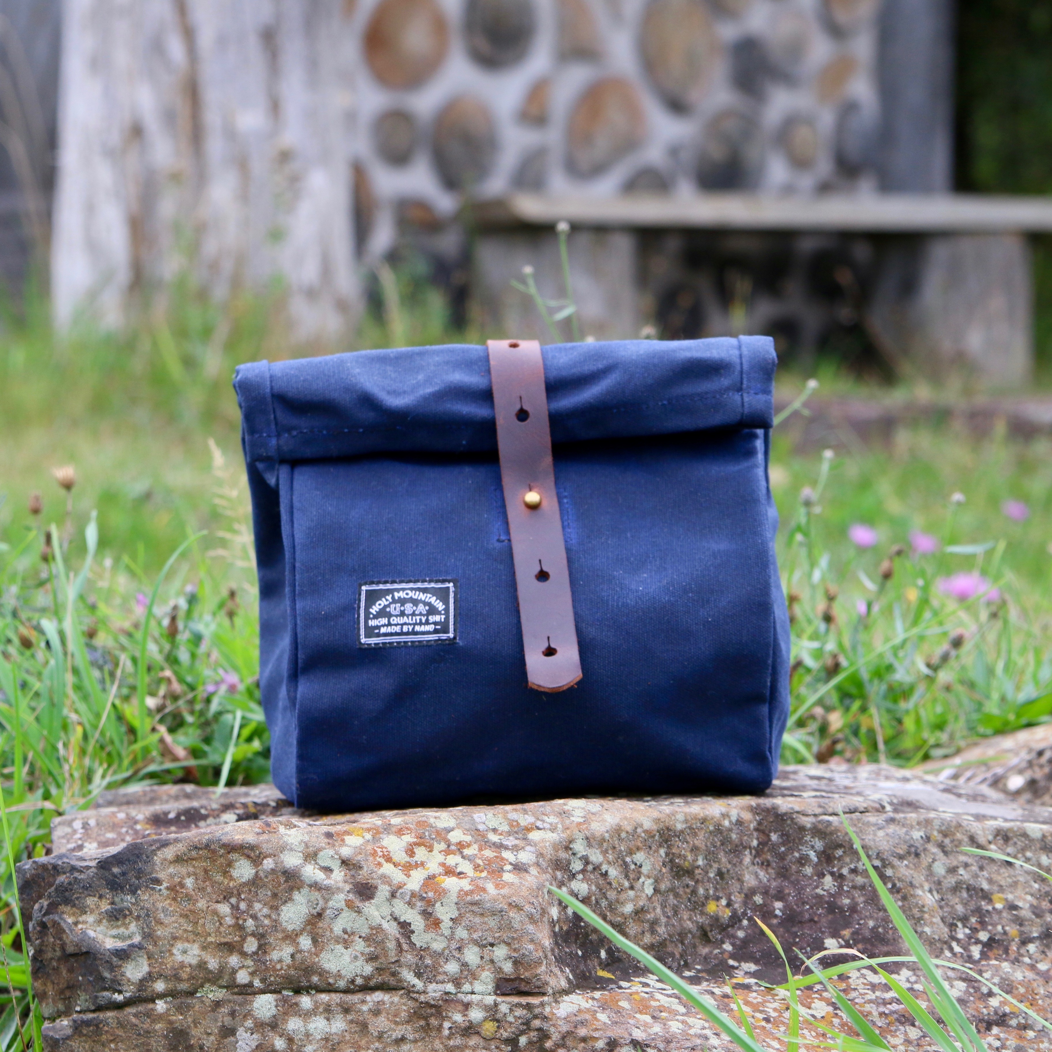 Holy Mountain lunch sack made of waxed canvas sitting on stone bench