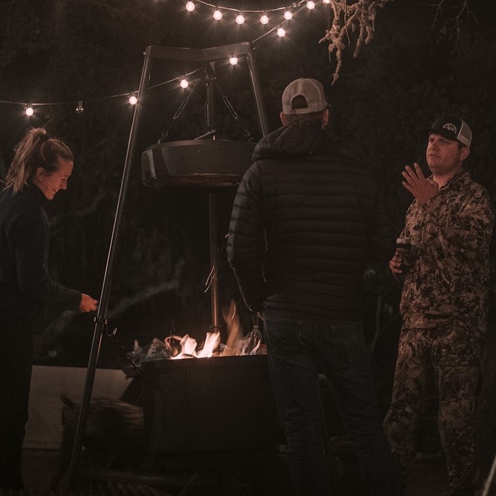 three people in puffy jackets and hats gathered around Burch Barrel fire pit