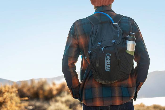 Person in burnt orange beanie and flannel facing away from camera wearing a Camelbak Pack