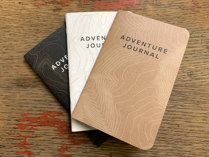 trio of adventure journal notebooks fanned out on table