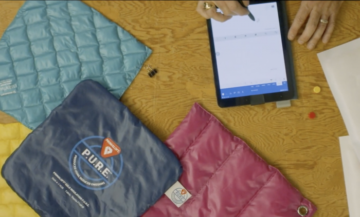 PrimaLoft P.U.R.E. manufacturing fabrics and designer with tablet at table