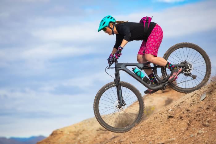 woman riding on a Salsa Cycles Warbird Apex down a dirt trail in pink shorts with a hip pack