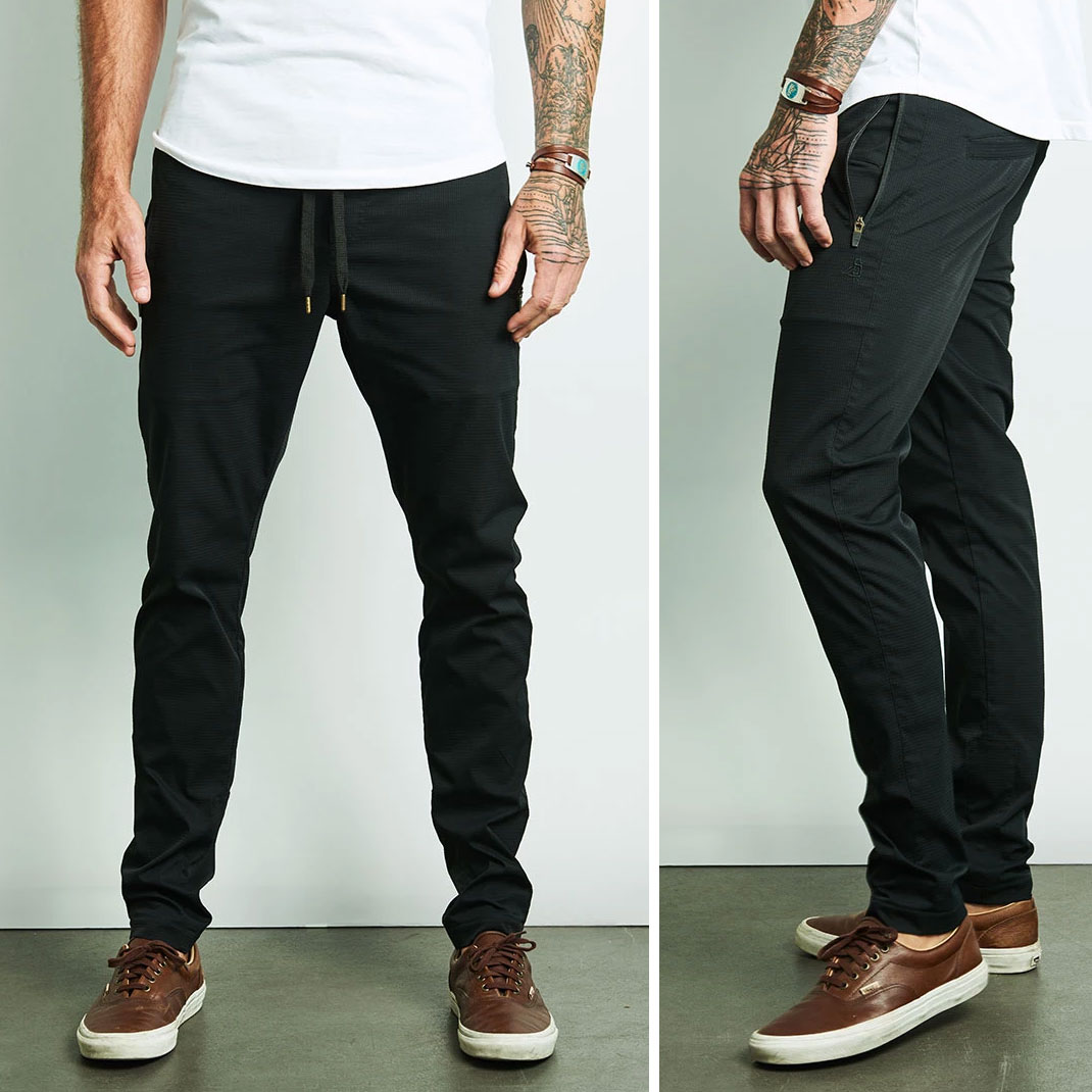 model with tattoos in white shirt, Walter Sky Outdoor Pants, and leather sneakers