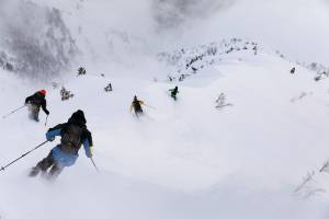 Four skiers descend a couloir in Faction Skis' film