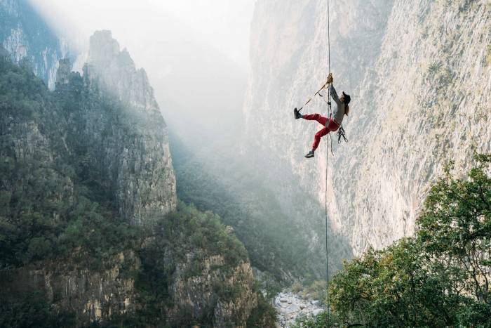 girl climbing up rope with the rockface not visible above her