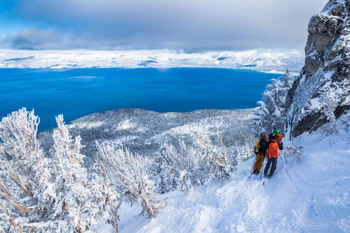 three people on backcountry ski tour in Tahoe looking out over crystal blue lake