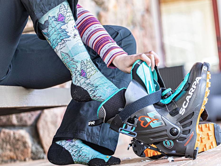 The Best Ski Socks of 2021 skier putting on Smartwool socks and ski boots